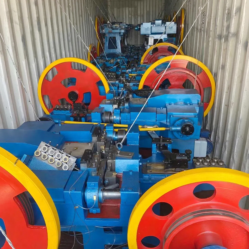 Industrial Processing Equipment Inside a Shipping Container Featuring Blue Machines with Large Red and yellow Wheels Arranged in a Row for Production Work