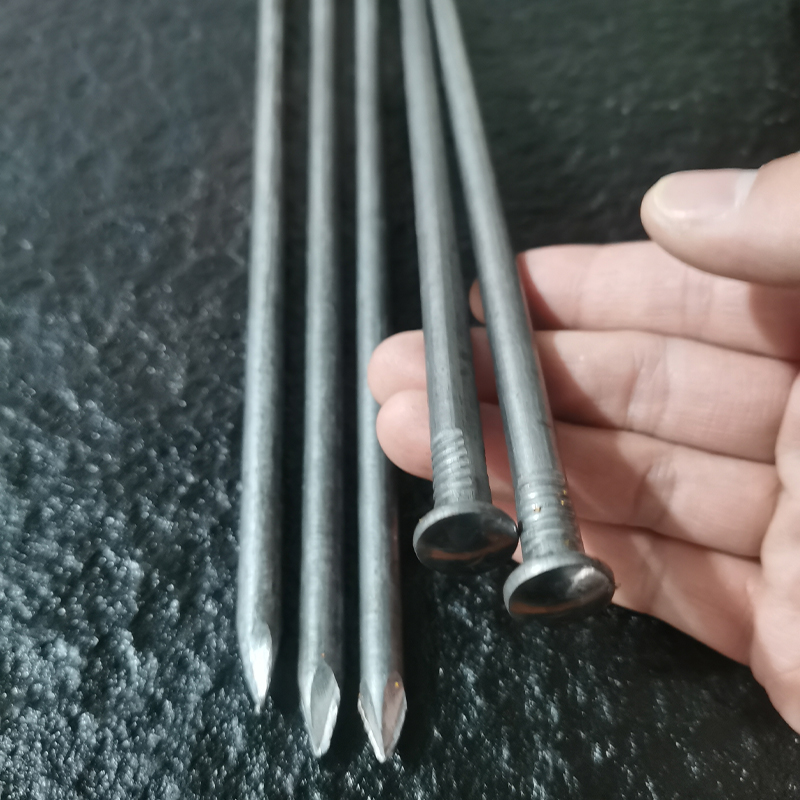 Close up of Four Metal Tools on a Dark Surface Two Nails and Two Slender Chisels or Punches Resting in a Hands Grasp