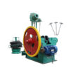 Industrial metal-forming press featuring a large red flywheel, green frame, and blue electric motor, with a wire spool on the left and nails on the right.